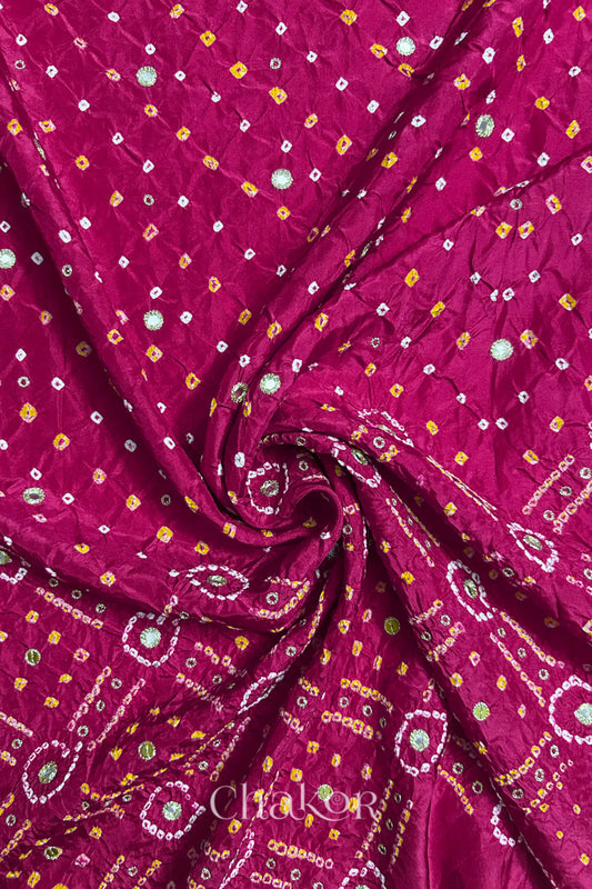 Rani Pink mulberry silk Bandhani (Rai Bandhej) fabric with white and yellow tie-dyed motifs, golden zari mirror and sequin embellishment, arranged in a swirling design  – CHAKOR.
