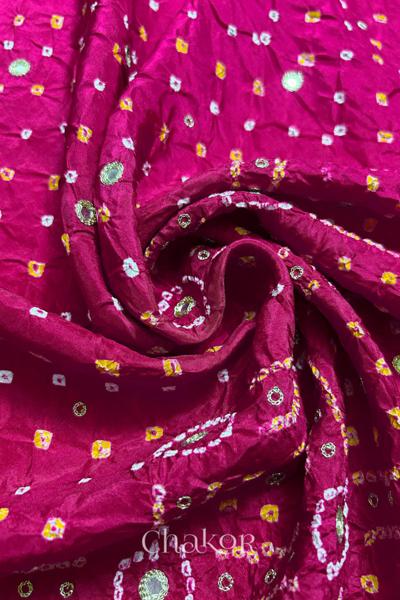Rani Pink mulberry silk Bandhani (Rai Bandhej) fabric with white and yellow tie-dyed motifs, golden zari mirror and sequin embellishment, arranged in a swirling design  – CHAKOR.
