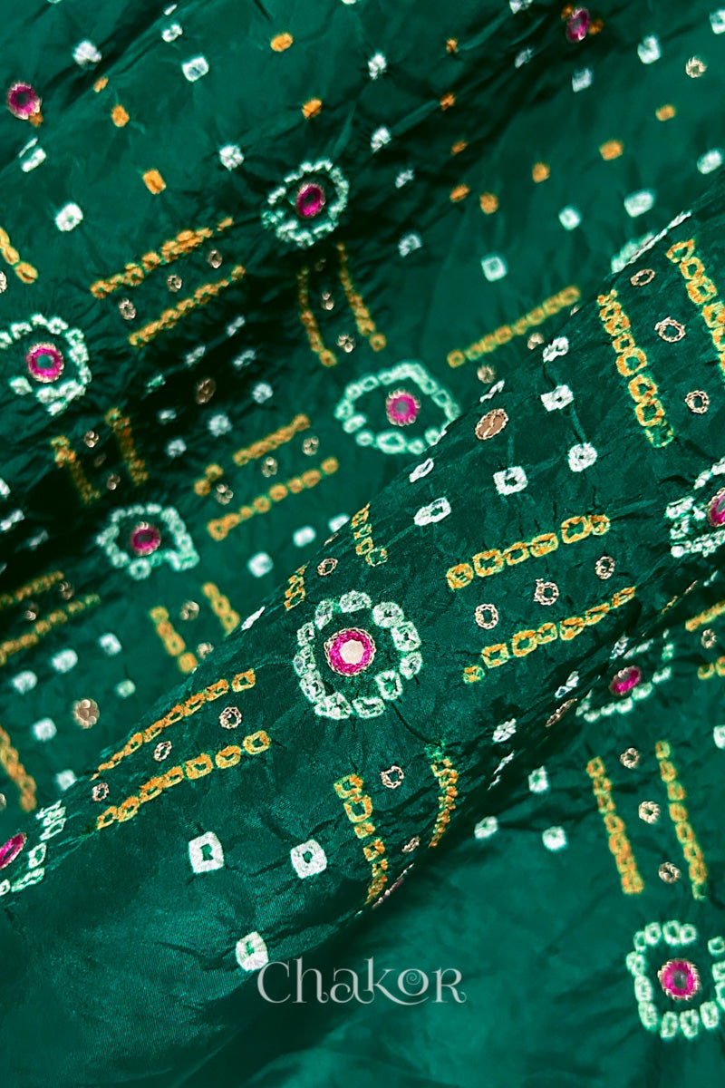 Close-up of green mulberry silk Bandhani (Rai Bandhej) fabric with white and yellow tie-dye motifs, pink embroidered mirror work and sequin detailing – CHAKOR.