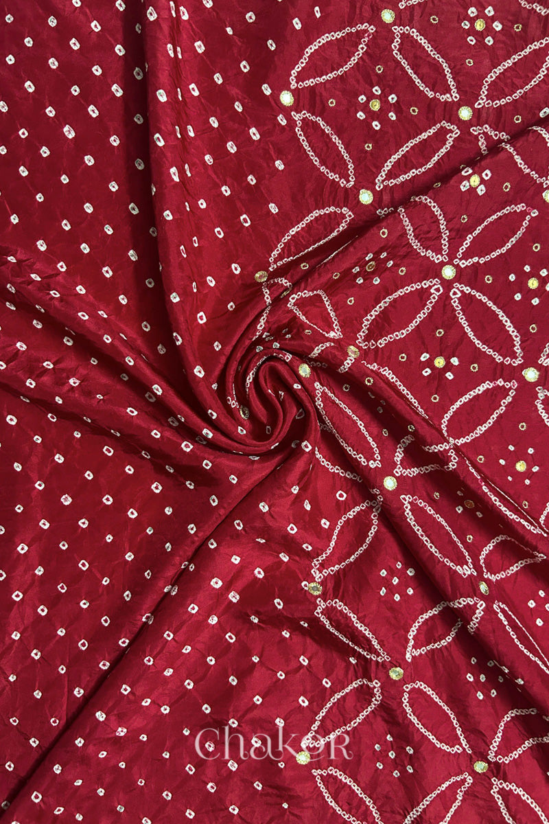 Deep Red mulberry silk Bandhani (Rai Bandhej) fabric with white tie-dyed motifs, golden zari mirror and sequin embellishment, arranged in a swirling design  – CHAKOR.
