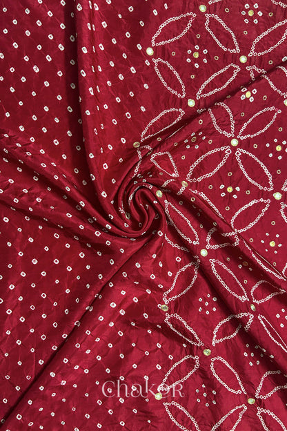 Deep Red mulberry silk Bandhani (Rai Bandhej) fabric with white tie-dyed motifs, golden zari mirror and sequin embellishment, arranged in a swirling design  – CHAKOR.
