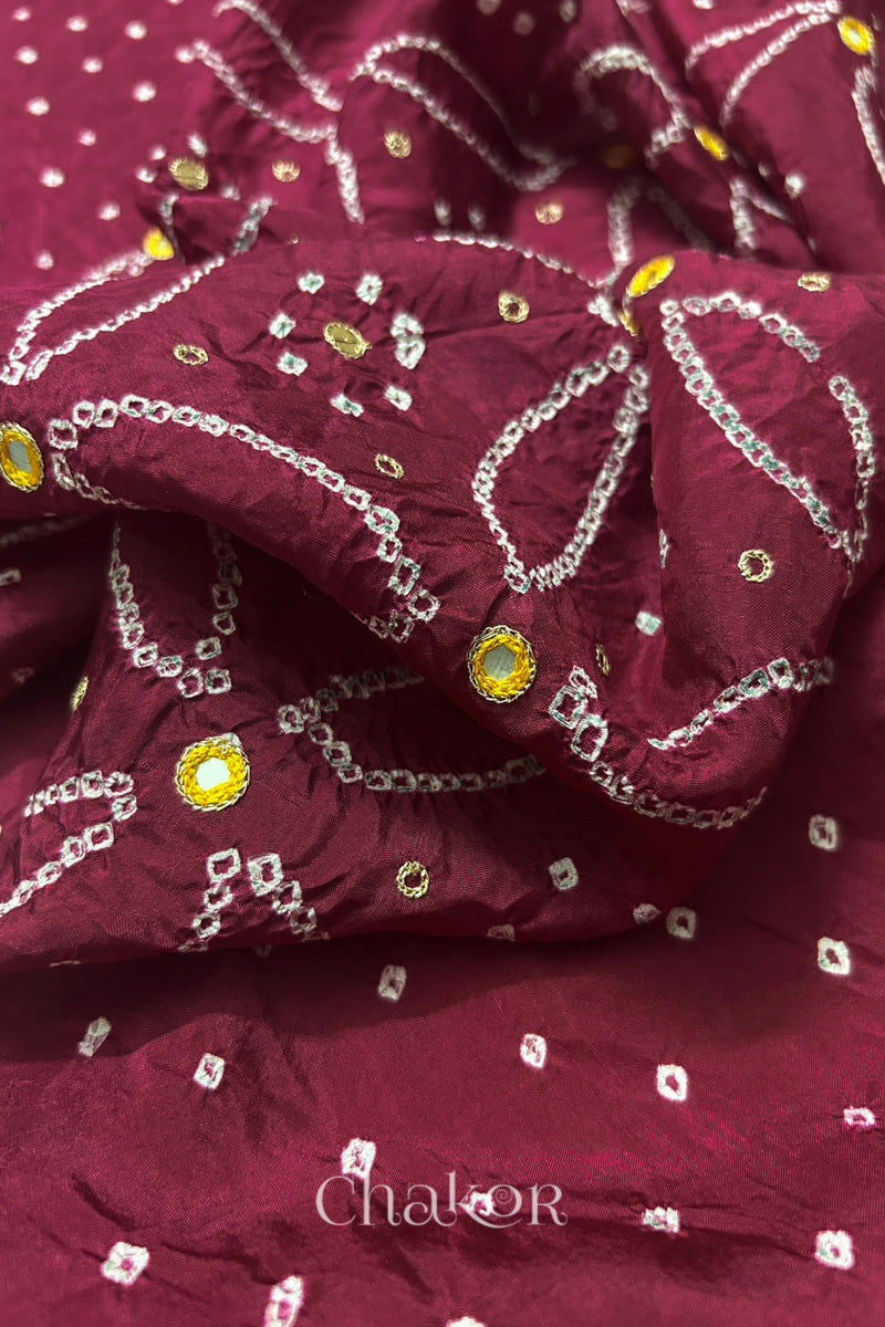 Close-up of Dusty Red mulberry silk Bandhani (Rai Bandhej) fabric with white tie-dye motifs, zari embroidered yellow mirror work and sequin detailing – CHAKOR.
