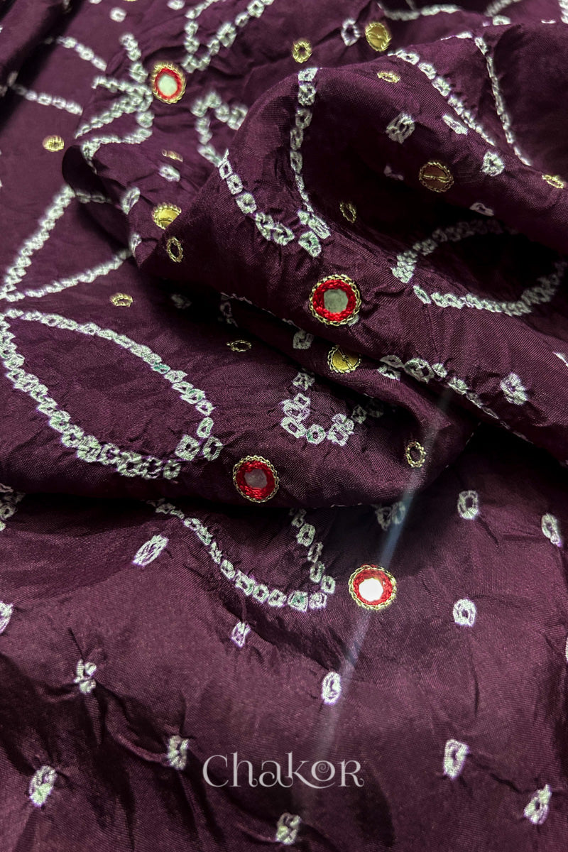 Close-up of Maroon mulberry silk Bandhani (Rai Bandhej) fabric with white tie-dye motifs, zari embroidered red mirror work and sequin detailing – CHAKOR.
