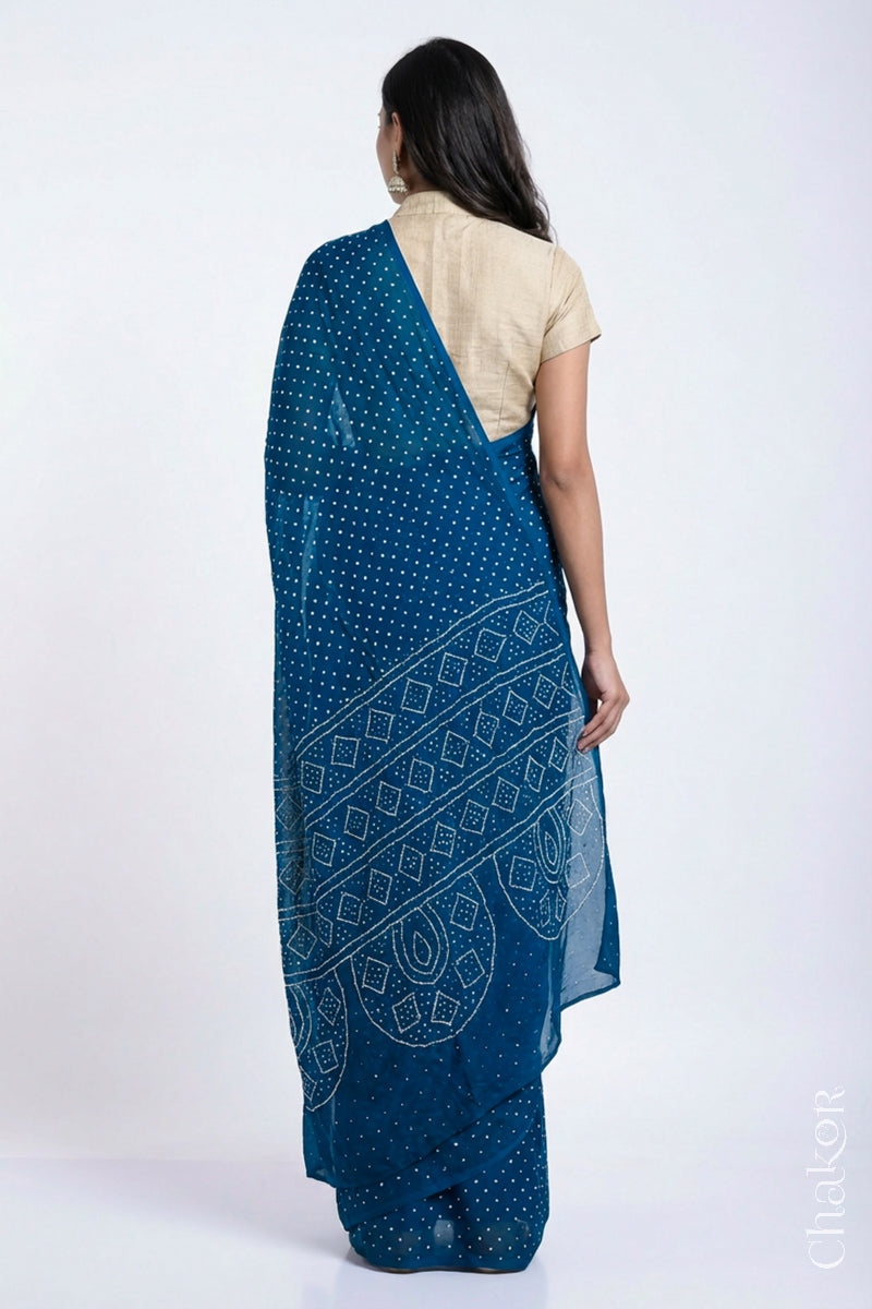Back view of model wearing indigo blue Bandhani Mulberry Silk Saree, handcrafted in rai bandhej patterns with mukaish embroidery.