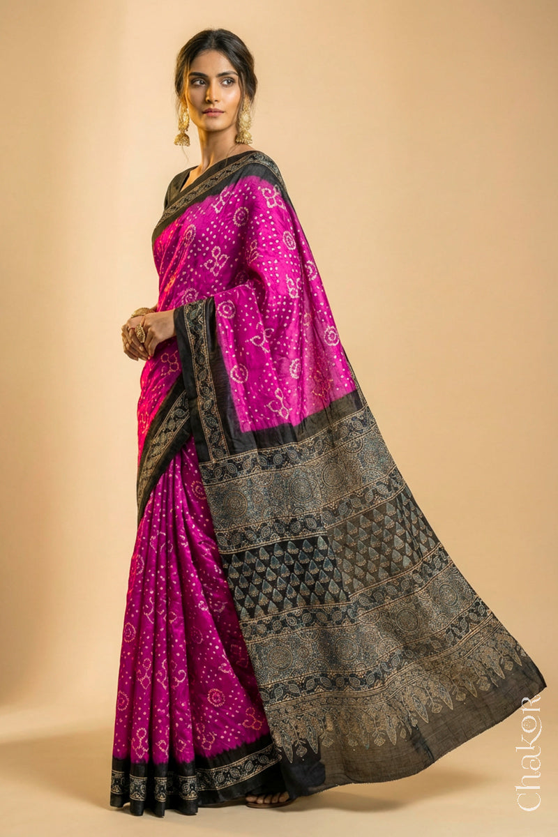 Woman wearing Pink Bandhani Saree with Black Ajrakh printed border and pallu in pure gaji silk with traditional bandhej tie-dye, handcrafted in Kutch. 