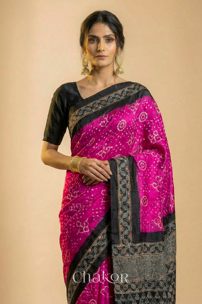 Woman wearing Pink Bandhani Saree with Black Ajrakh printed border and pallu in pure gaji silk with traditional bandhej tie-dye, handcrafted in Kutch. 