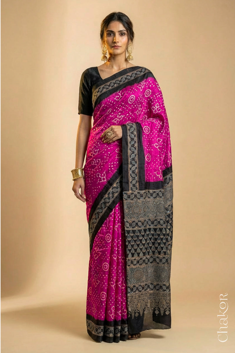 Woman wearing Pink Bandhani Saree with Black Ajrakh printed border and pallu in pure gaji silk with traditional bandhej tie-dye, handcrafted in Kutch. 