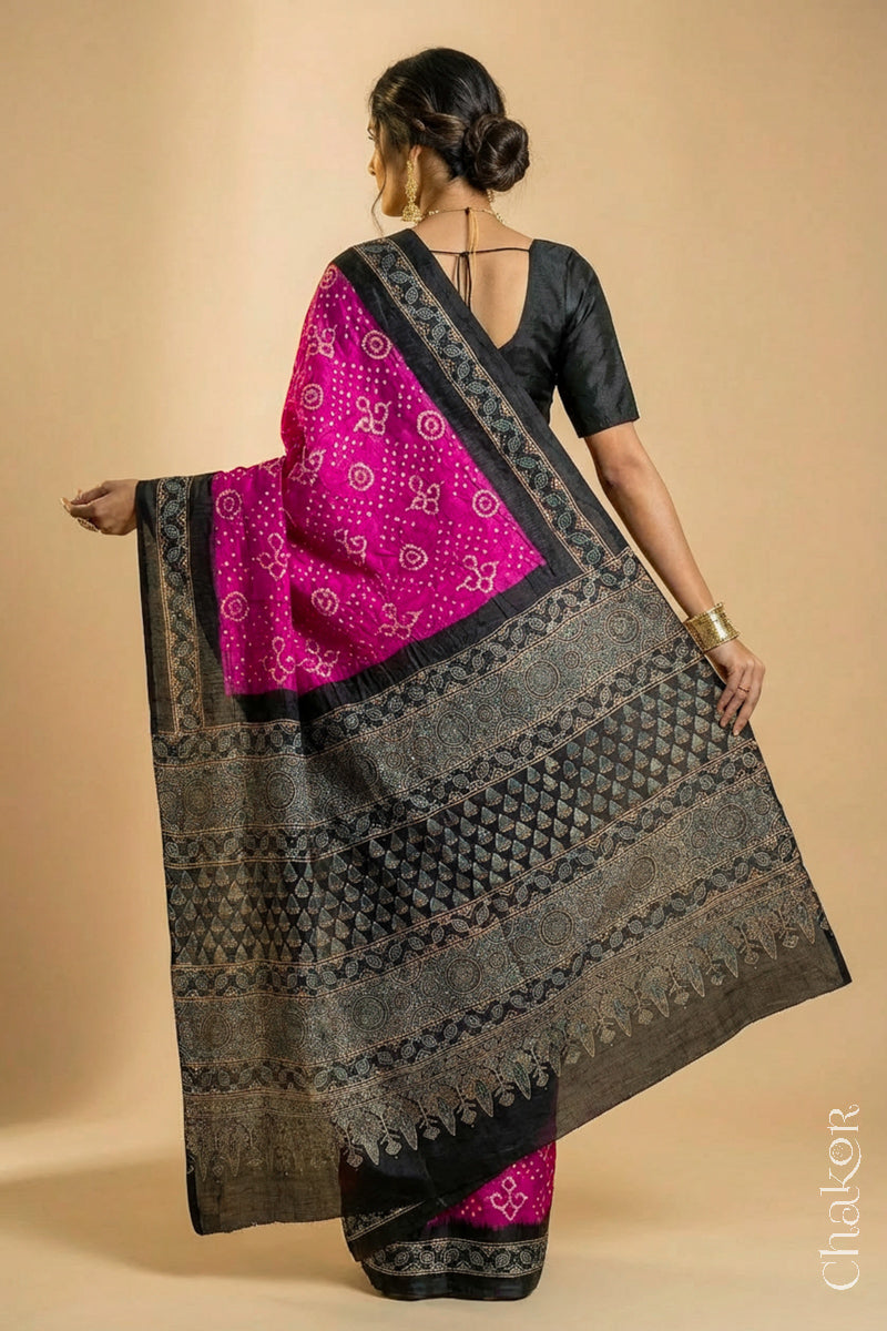 Woman wearing Pink Bandhani Saree with Black Ajrakh printed border and pallu in pure gaji silk with traditional bandhej tie-dye, handcrafted in Kutch. 