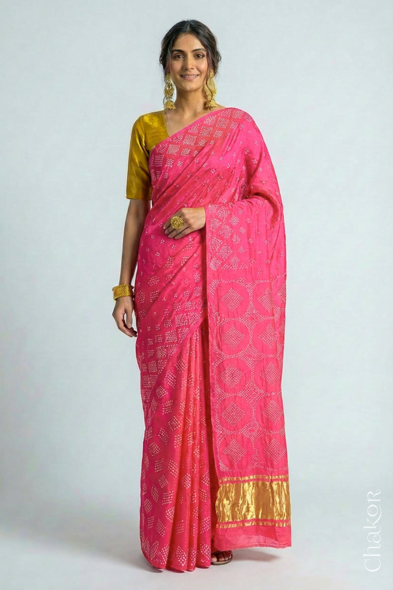 Model wearing Handcrafted Coral Pink Bandhani Gaji Silk Saree with rai bandhej patterns and tissue pallu.