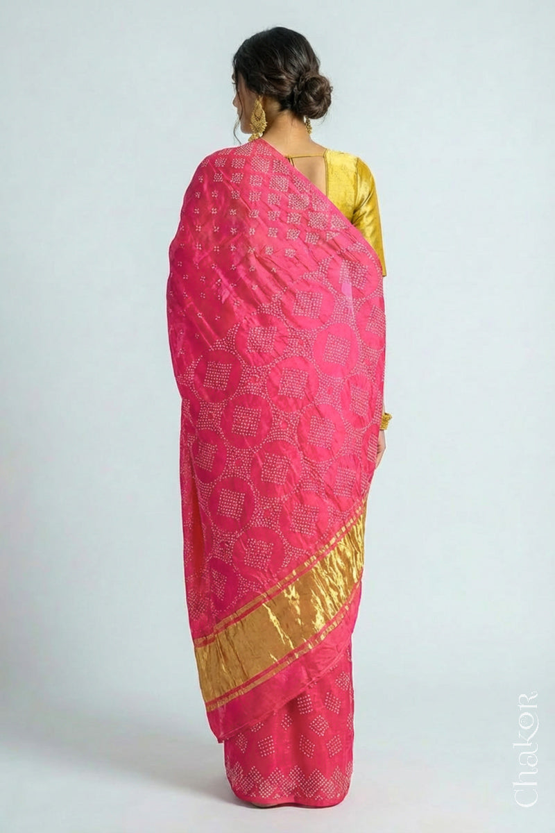 Back view of Model wearing Handcrafted Coral Pink Bandhani Gaji Silk Saree with rai bandhej patterns and tissue pallu.