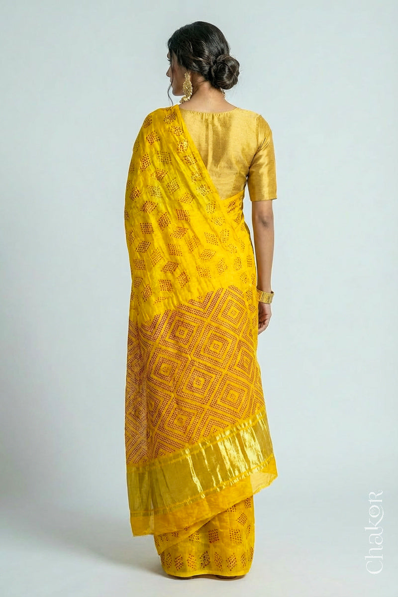 Backview of model wearing Yellow Red Bandhani Gaji Silk Saree, handcrafted with red rai bandhej motifs and lagdi patto pallu.