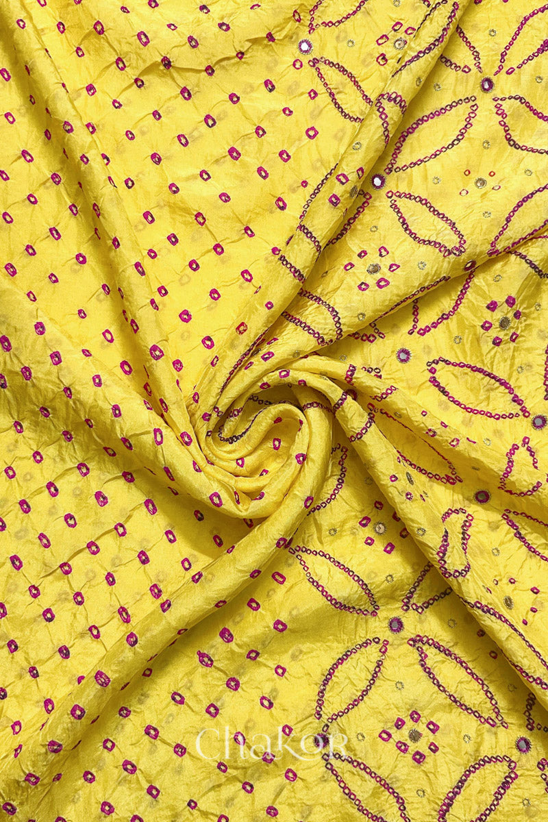 Yellow mulberry silk Bandhani (Rai Bandhej) fabric with rani pink tie-dyed motifs, pink with zari mirror and sequin embellishment, arranged in a swirling design  – CHAKOR.
