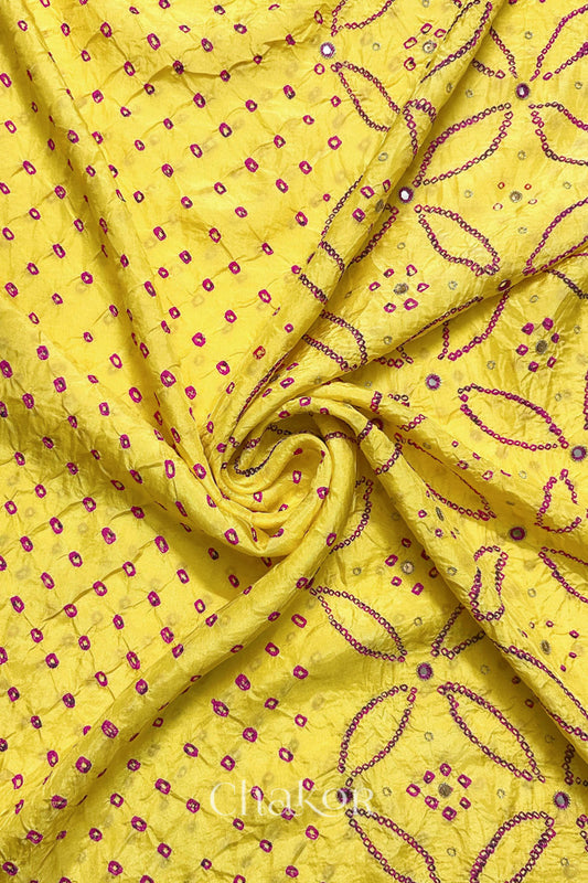Yellow mulberry silk Bandhani (Rai Bandhej) fabric with rani pink tie-dyed motifs, pink with zari mirror and sequin embellishment, arranged in a swirling design  – CHAKOR.
