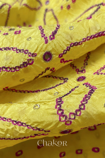 Close-up of Yellow mulberry silk Bandhani (Rai Bandhej) fabric with rani pink tie-dye motifs, zari embroidered pink mirror work and sequin detailing – CHAKOR.