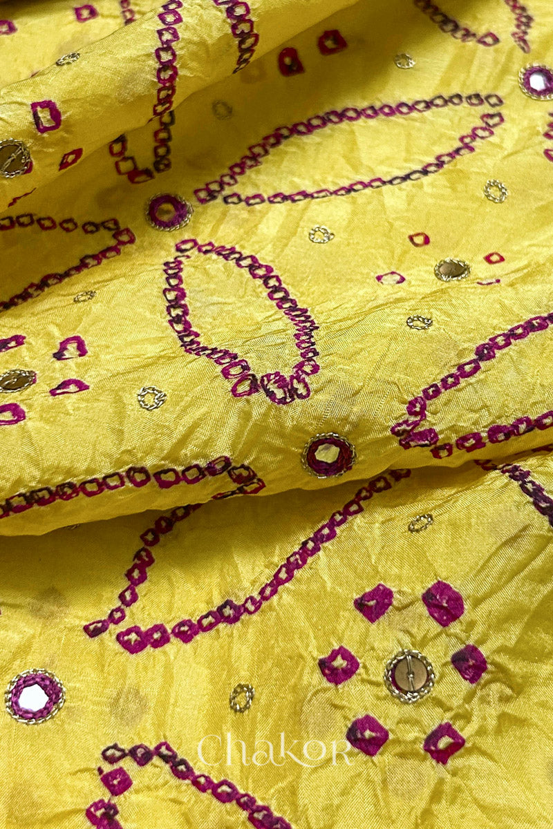 Close-up of Yellow mulberry silk Bandhani (Rai Bandhej) fabric with rani pink tie-dye motifs, zari embroidered pink mirror work and sequin detailing – CHAKOR.
