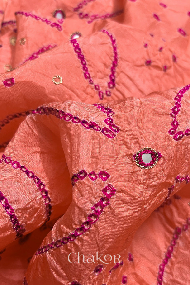 Close-up of Coral pink mulberry silk Bandhani (Rai Bandhej) fabric with rani pink tie-dye motifs, zari embroidered pink mirror work and sequin detailing – CHAKOR.
