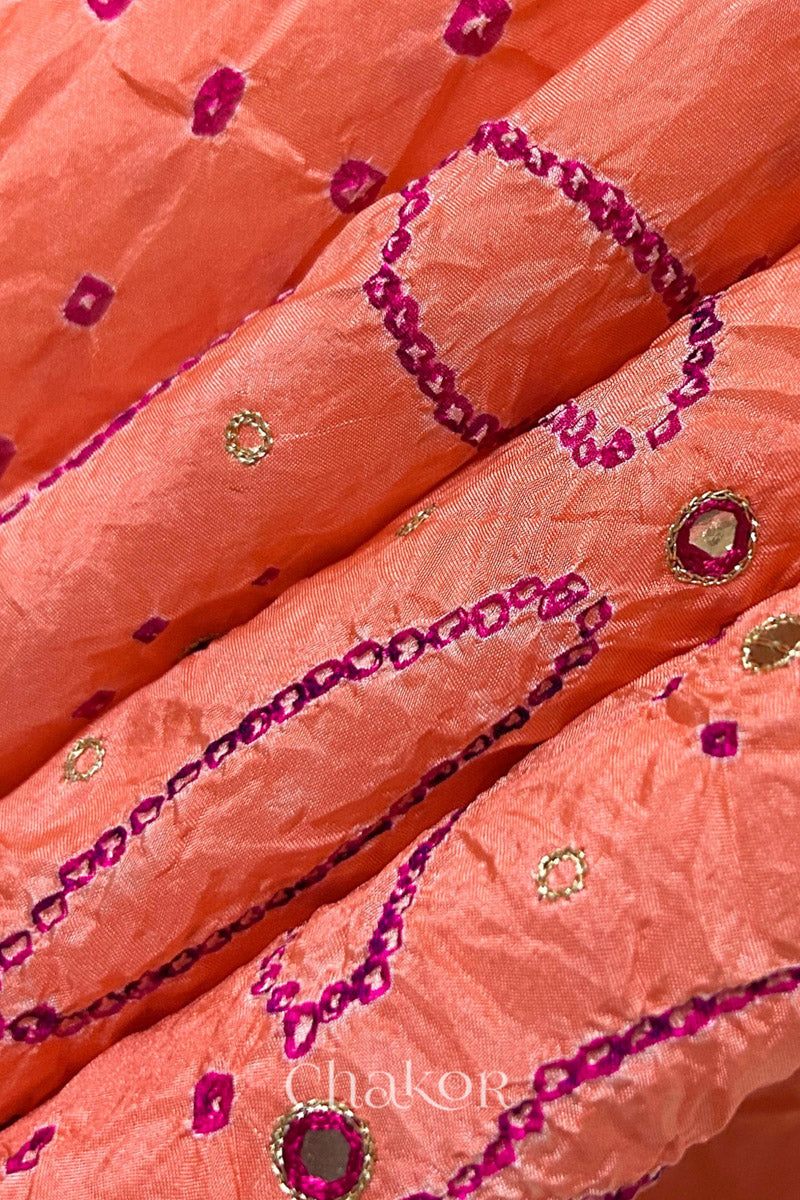 Close-up of Coral pink mulberry silk Bandhani (Rai Bandhej) fabric with rani pink tie-dye motifs, zari embroidered pink mirror work and sequin detailing – CHAKOR.
