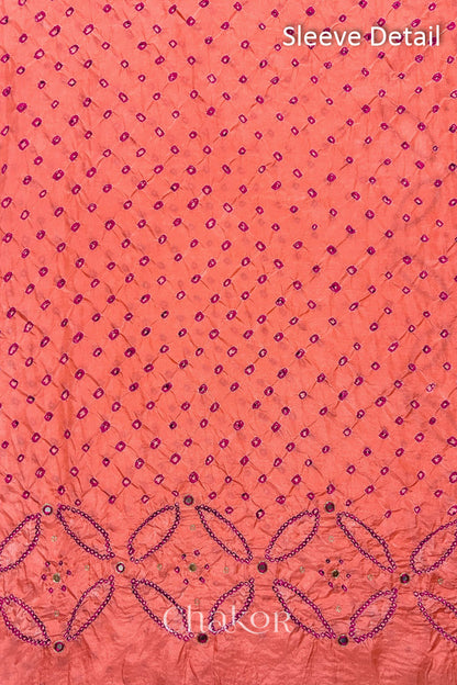 Sleeve detail of Coral pink mulberry silk Bandhani (Rai Bandhej) fabric with rani pink dots, floral bandhej borders and pink with zari mirror embroidery – CHAKOR.
