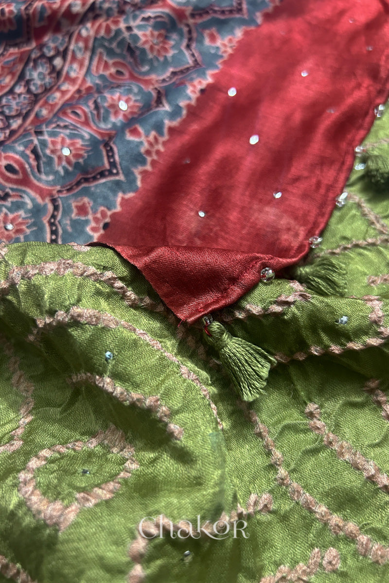 Pallu edge tassel detail of leaf green Bandhani gaji silk dupatta with Ajrakh print and madder red section.