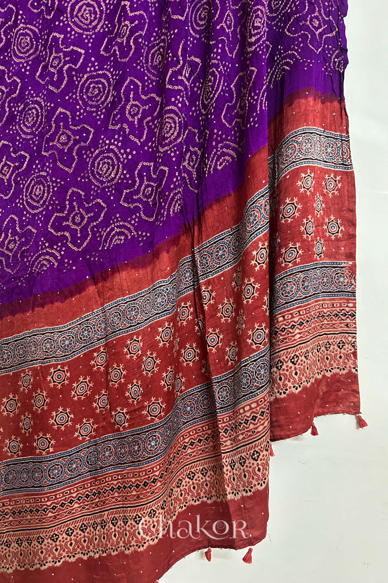 Hanging view of purple Bandhani gaji silk dupatta highlighting Ajrakh pallu edged with tassels.