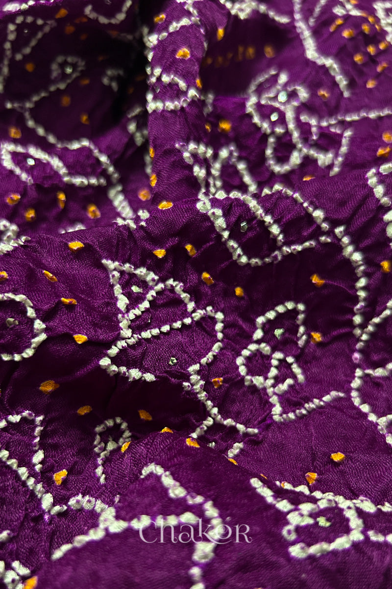 Close-up of a rai bandhej dupatta in magenta featuring white & yellow bandhani dots along with mukaish embroidery.Text reads Chakor brand watermark.
