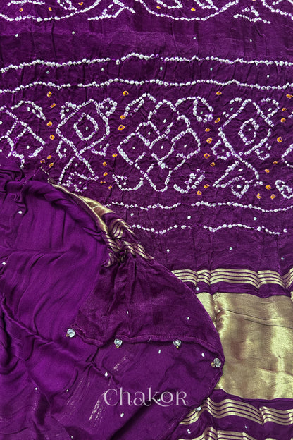 A colourful dupatta showcasing rai bandhej in magenta accented with mukaish work with tissue band folded on corner. Text reads Chakor brand watermark.
