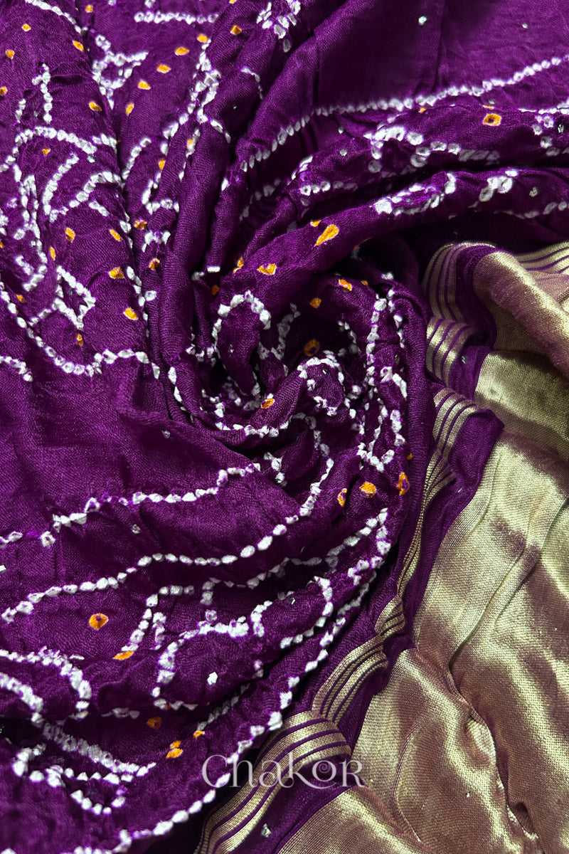 A colourful dupatta showcasing rai bandhej in magenta with golden tissue band placed in swirling style. Text reads Chakor brand watermark.

