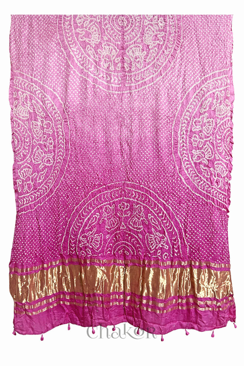 A vibrant pink ombre dyed dupatta showcasing intricate rai bandhej with a shimmering gold band on the pallu and tassels on the hem. Text reads Chakor brand watermark.
