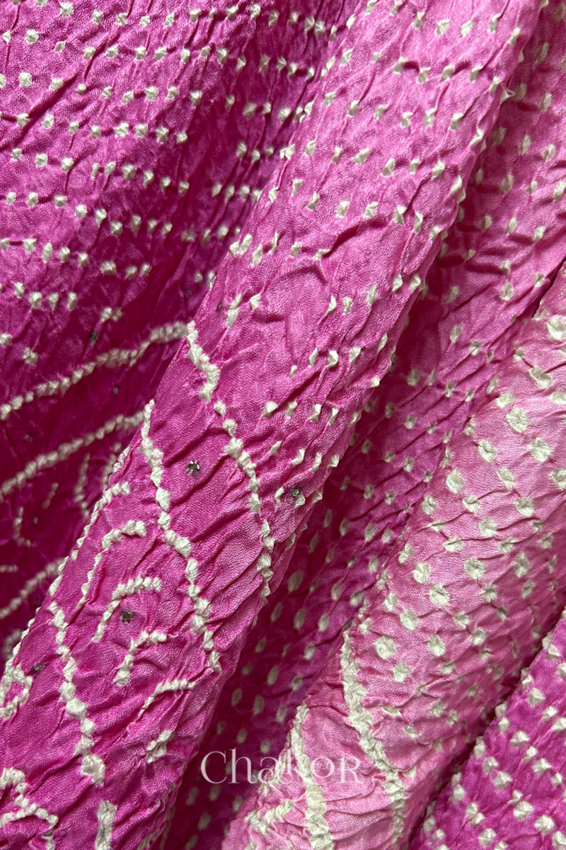 Close-up of a rai bandhej dupatta in pink ombre dyed featuring white bandhani dots along with mukaish embroidery.Text reads Chakor brand watermark.
