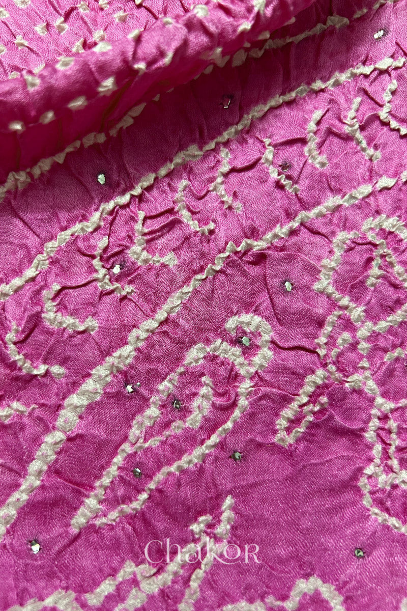 Close-up of a rai bandhej dupatta in pink ombre dyed featuring white bandhani dots along with mukaish embroidery.Text reads Chakor brand watermark.
