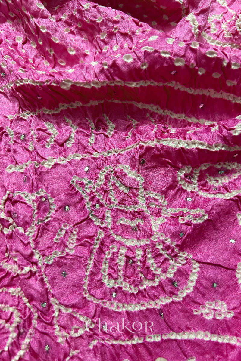 Close-up of a rai bandhej dupatta in pink ombre dyed featuring white bandhani dots along with mukaish embroidery.Text reads Chakor brand watermark.
