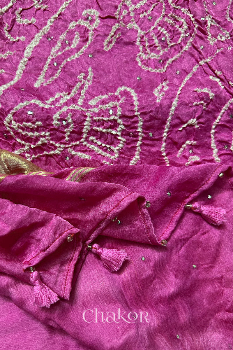 Close-up of a rai bandhej dupatta in pink ombre featuring tassel detail on the folded hem.Text reads Chakor brand watermark.
