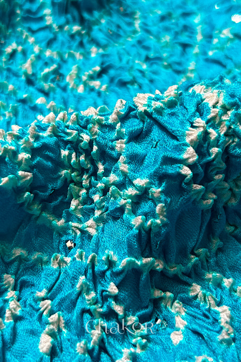 Close-up of a rai bandhej dupatta in blue ombre dyed featuring white bandhani dots along with mukaish embroidery.Text reads Chakor brand watermark.
