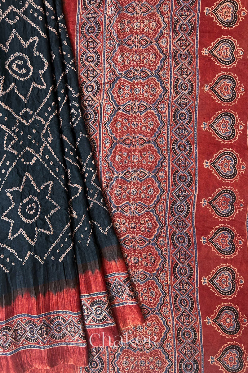 Close up of Black Bandhani Saree with Natural Red Ajrakh printed border and pallu in pure gaji silk with traditional bandhej tie-dye, handcrafted in Kutch. 
