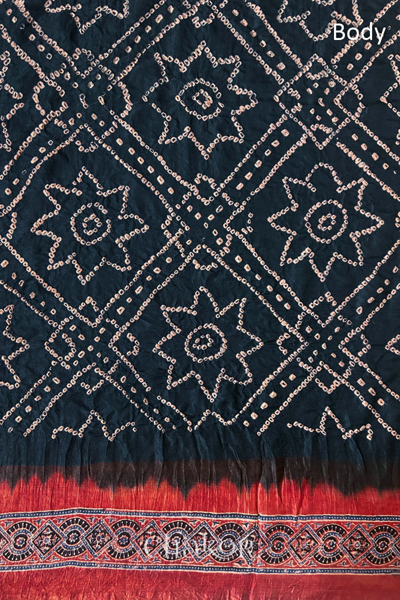 Close up of Black Bandhani Saree with Natural Red Ajrakh printed border and pallu in pure gaji silk with traditional bandhej tie-dye, handcrafted in Kutch. 