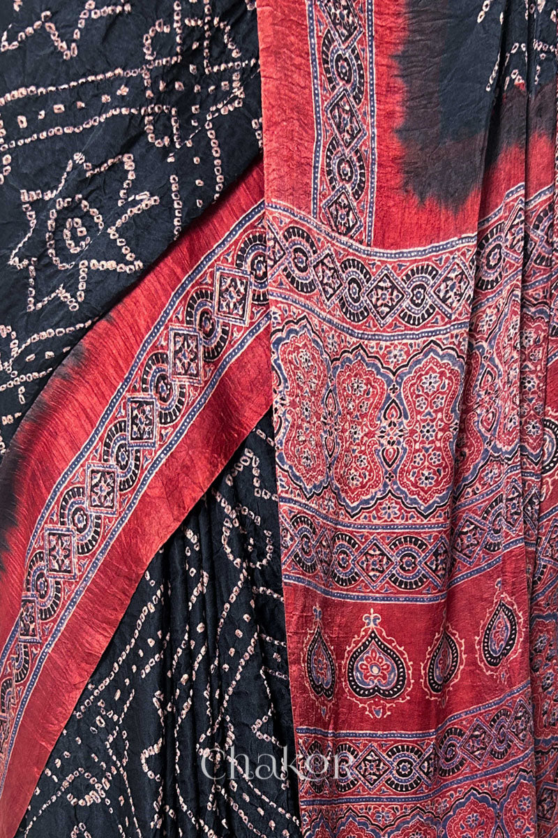 Close up of Black Bandhani Saree with Natural Red Ajrakh printed border and pallu in pure gaji silk with traditional bandhej tie-dye, handcrafted in Kutch. 