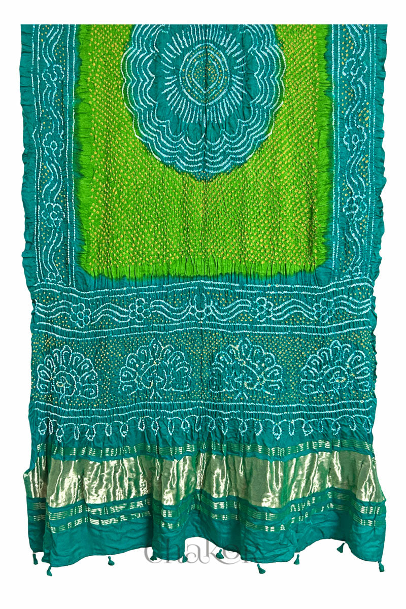 A vibrant Jade & parrot green dual colour dupatta showcasing intricate rai bandhej in red & yellow with a shimmering gold band on the pallu and tassels on the hem. Text reads Chakor brand watermark.
