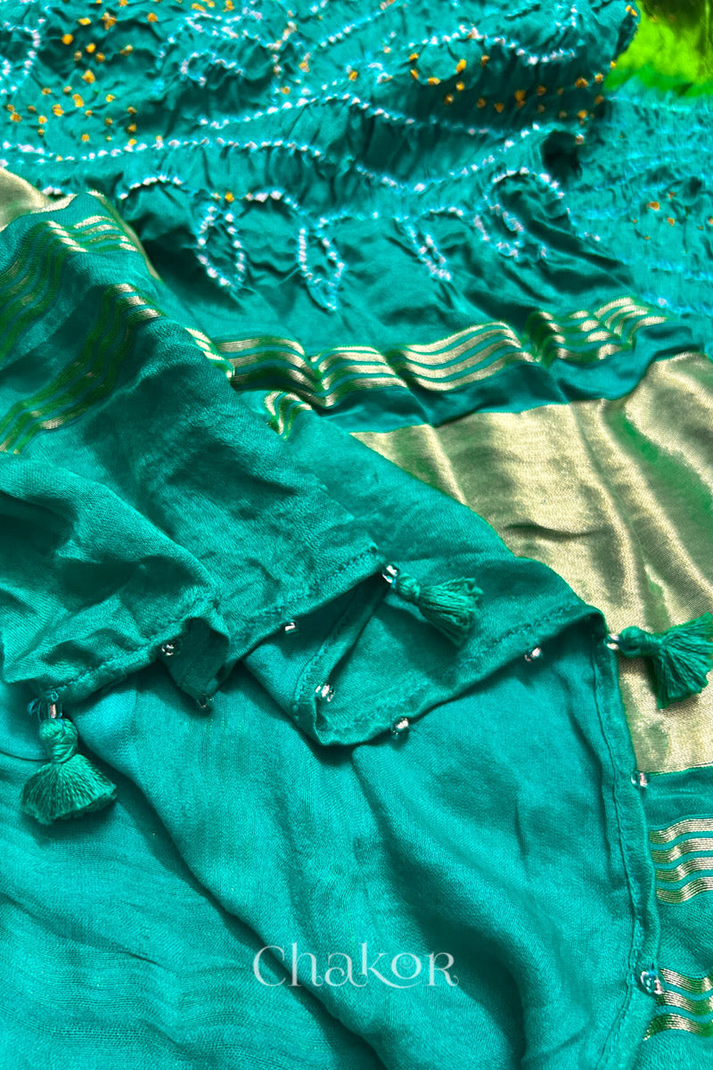 Close-up of a rai bandhej dupatta in Jade & parrot green dual colour featuring tassel detail on the folded hem.Text reads Chakor brand watermark.
