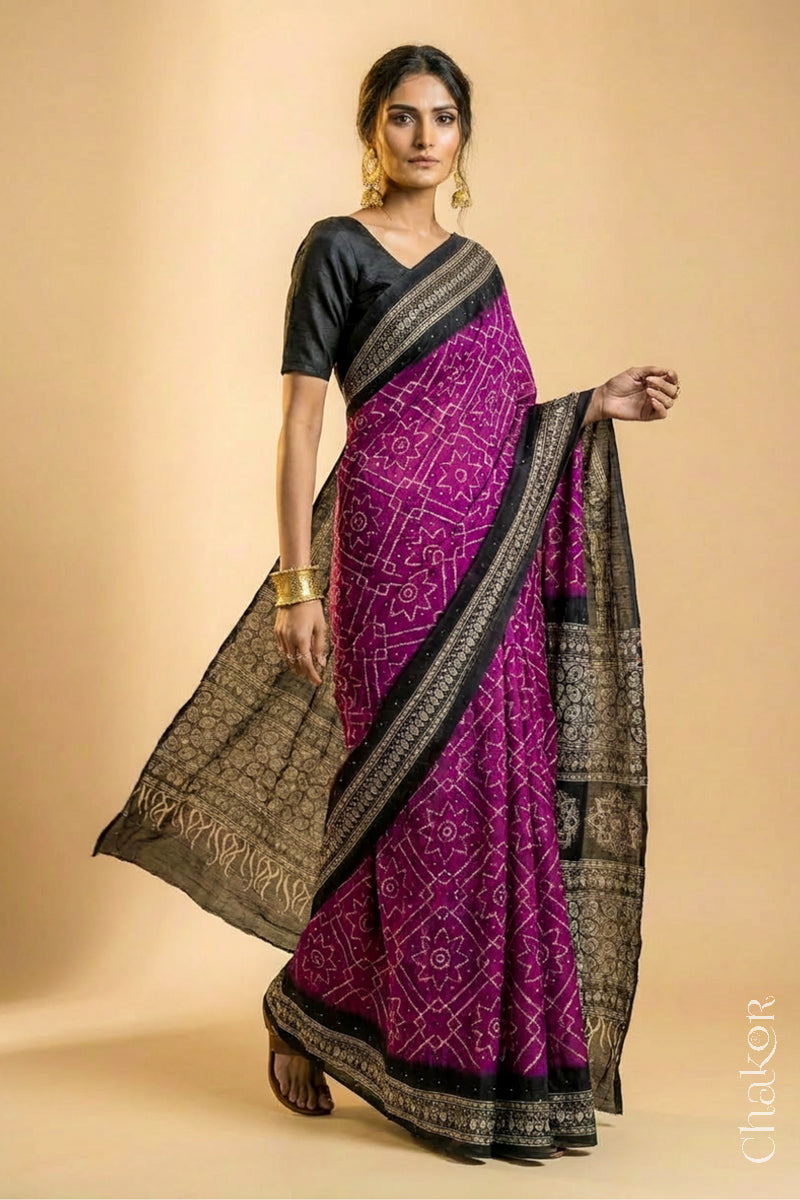 Woman wearing Magenta Bandhani Saree with Natural Black Ajrakh printed border and pallu in pure gaji silk with traditional bandhej tie-dye & mukaish embroidery, handcrafted in Kutch. 