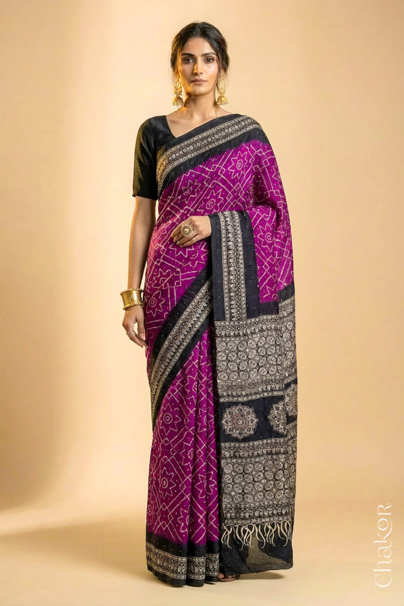 Woman wearing Magenta Bandhani Saree with Natural Black Ajrakh printed border and pallu in pure gaji silk with traditional bandhej tie-dye & mukaish embroidery, handcrafted in Kutch. 
