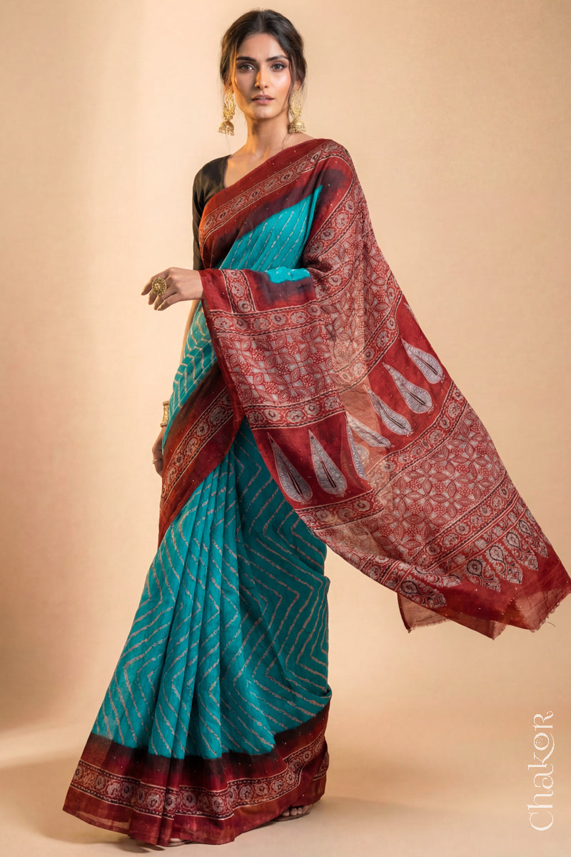 Woman wearing Peacock Blue Bandhani Saree with Natural Red Ajrakh printed border and pallu in pure gaji silk with traditional bandhej tie-dye & mukaish embroidery, handcrafted in Kutch. 