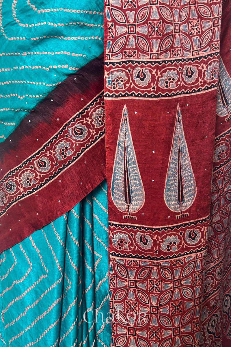 Woman wearing Peacock Blue Bandhani Saree with Natural Red Ajrakh printed border and pallu in pure gaji silk with traditional bandhej tie-dye & mukaish embroidery, handcrafted in Kutch. 