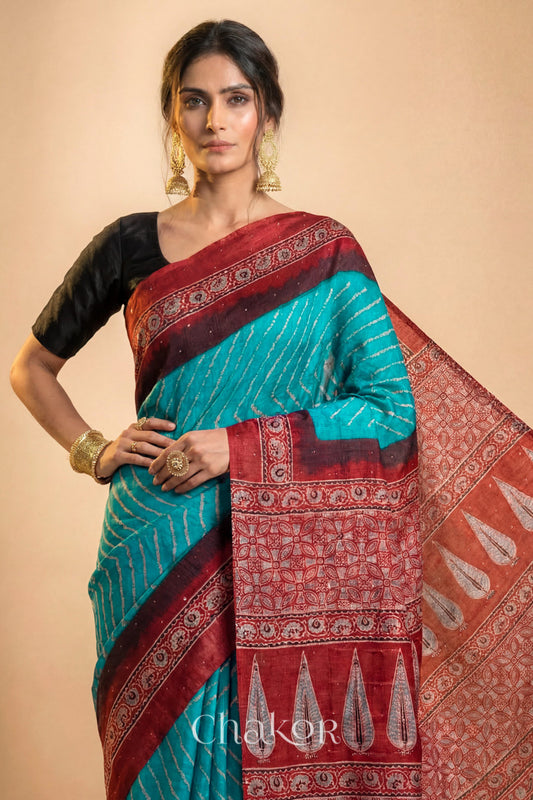 Woman wearing Peacock Blue Bandhani Saree with Natural Red Ajrakh printed border and pallu in pure gaji silk with traditional bandhej tie-dye & mukaish embroidery, handcrafted in Kutch. 