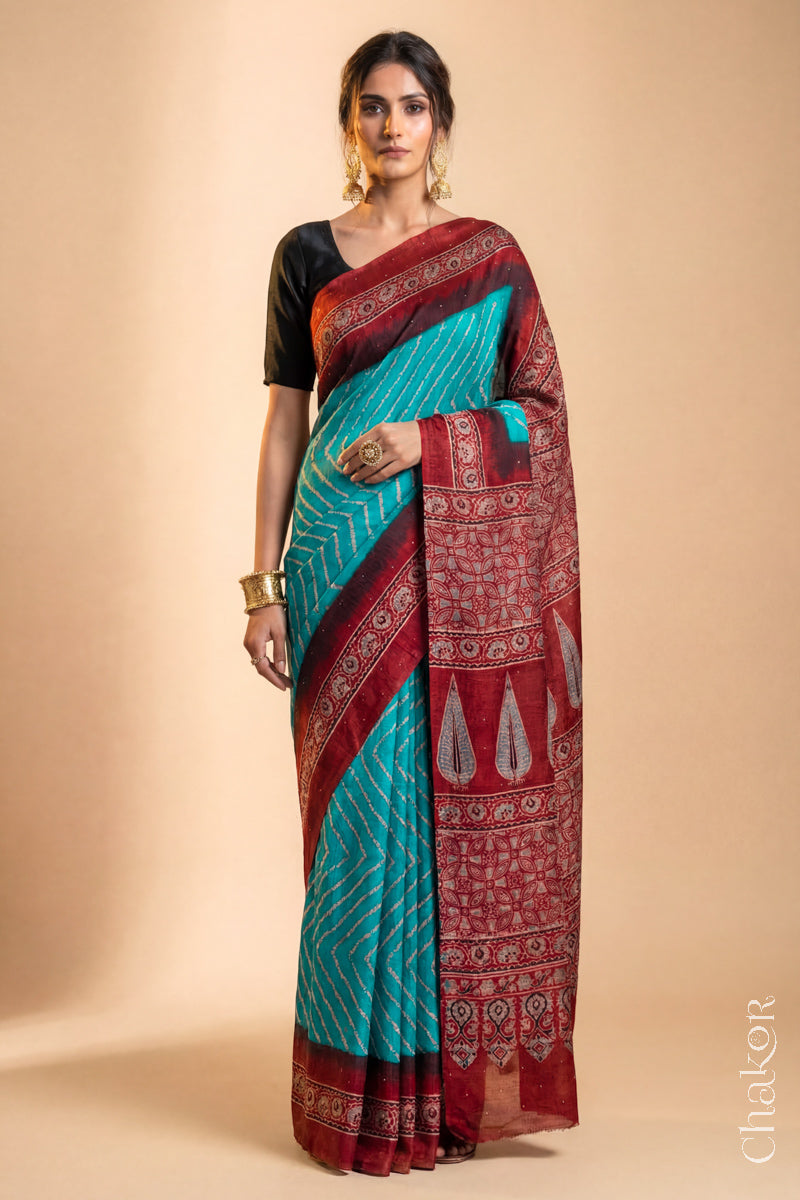 Woman wearing Peacock Blue Bandhani Saree with Natural Red Ajrakh printed border and pallu in pure gaji silk with traditional bandhej tie-dye & mukaish embroidery, handcrafted in Kutch. 