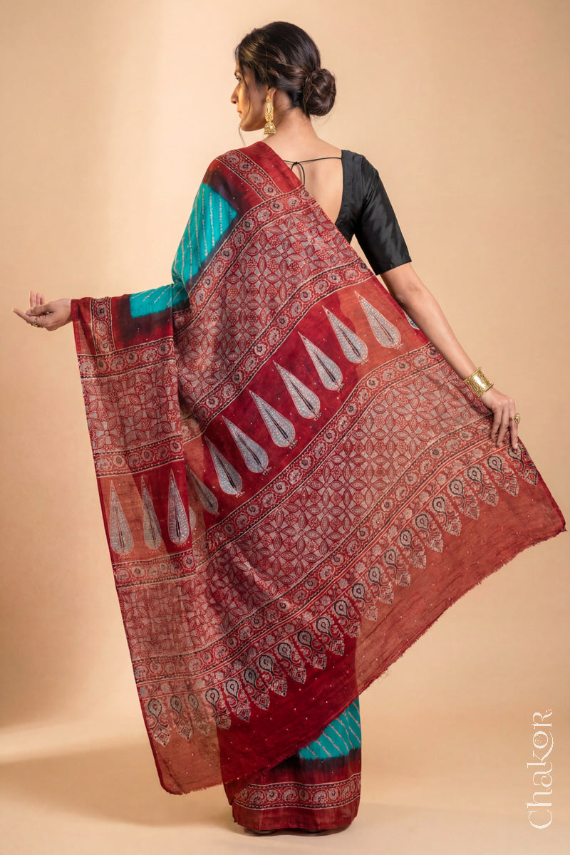 Woman wearing Peacock Blue Bandhani Saree with Natural Red Ajrakh printed border and pallu in pure gaji silk with traditional bandhej tie-dye & mukaish embroidery, handcrafted in Kutch. 