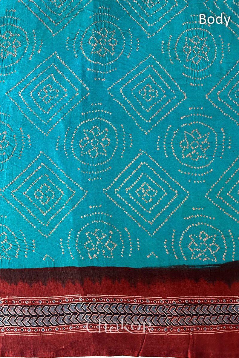 Close up of Peacock Blue Bandhani Saree with Natural Red Ajrakh printed border and pallu in pure gaji silk with traditional bandhej tie-dye, handcrafted in Kutch. 