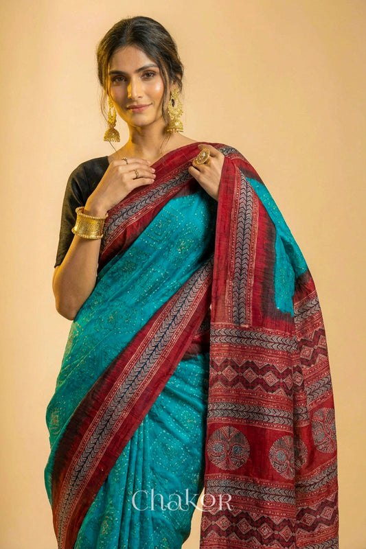 Woman wearing Peacock Blue Bandhani Saree with Natural Red Ajrakh printed border and pallu in pure gaji silk with traditional bandhej tie-dye, handcrafted in Kutch. 