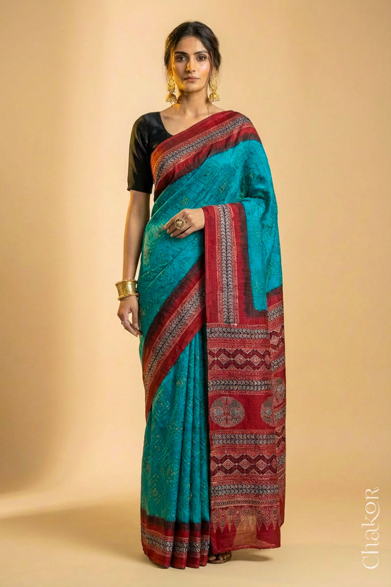 Woman wearing Peacock Blue Bandhani Saree with Natural Red Ajrakh printed border and pallu in pure gaji silk with traditional bandhej tie-dye, handcrafted in Kutch. 