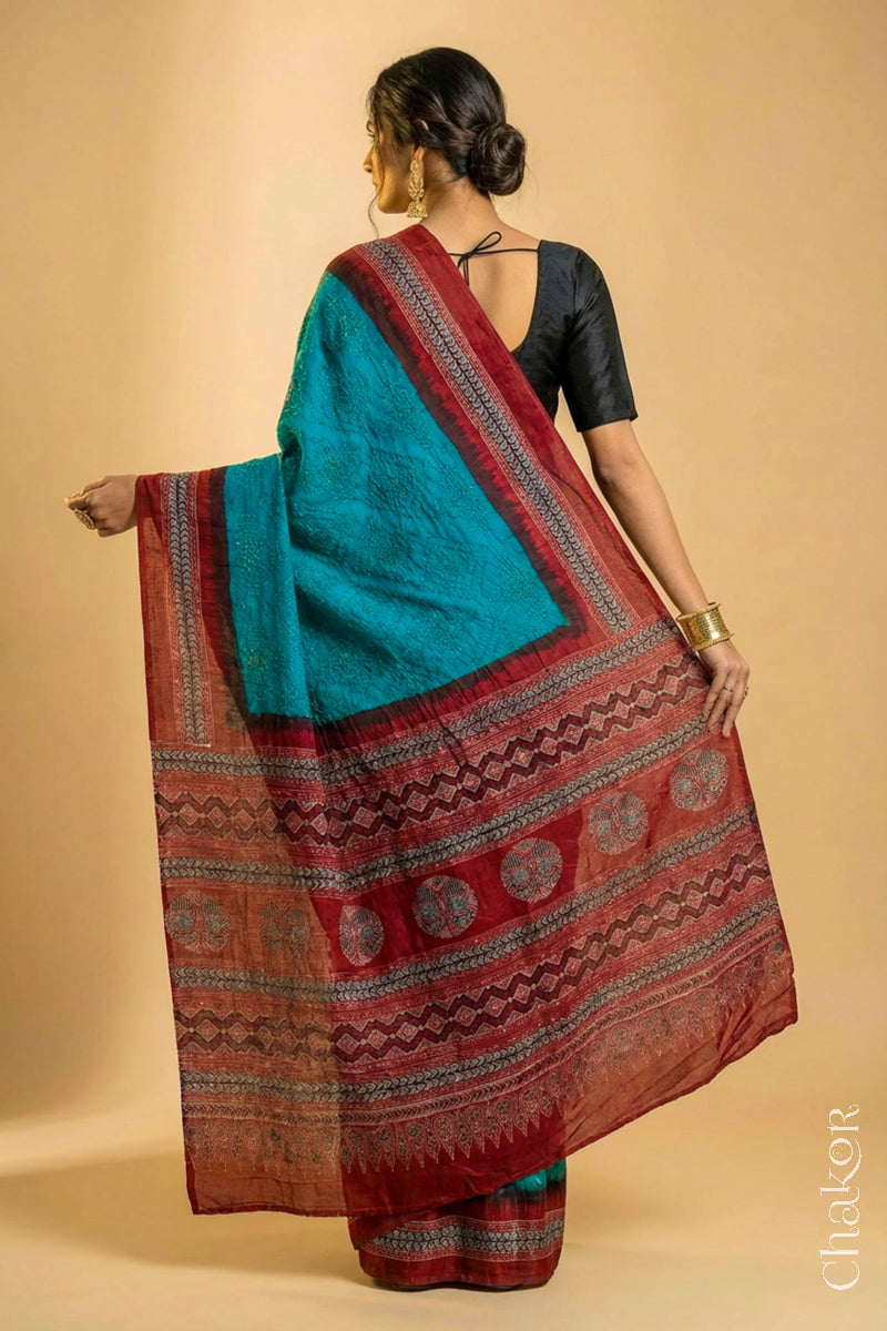 Woman wearing Peacock Blue Bandhani Saree with Natural Red Ajrakh printed border and pallu in pure gaji silk with traditional bandhej tie-dye, handcrafted in Kutch. 