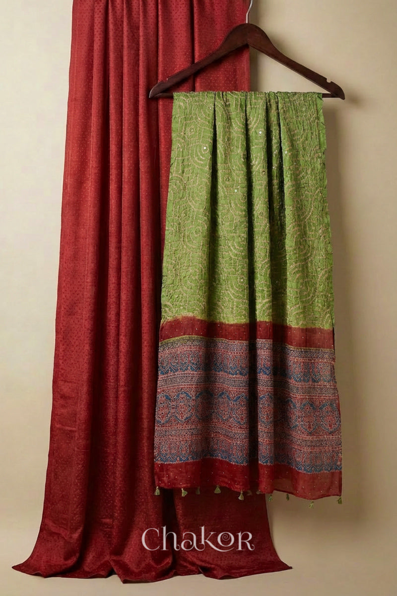 Brick red mashru kurta set fabric styled with green bandhani silk hand embroidered dupatta and ajrakh printed pallu.